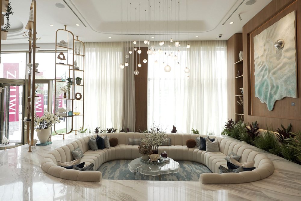 Beach Walk Residence A stylish lounge area featuring a curved sofa, modern lighting, and decorative plants, with large windows.